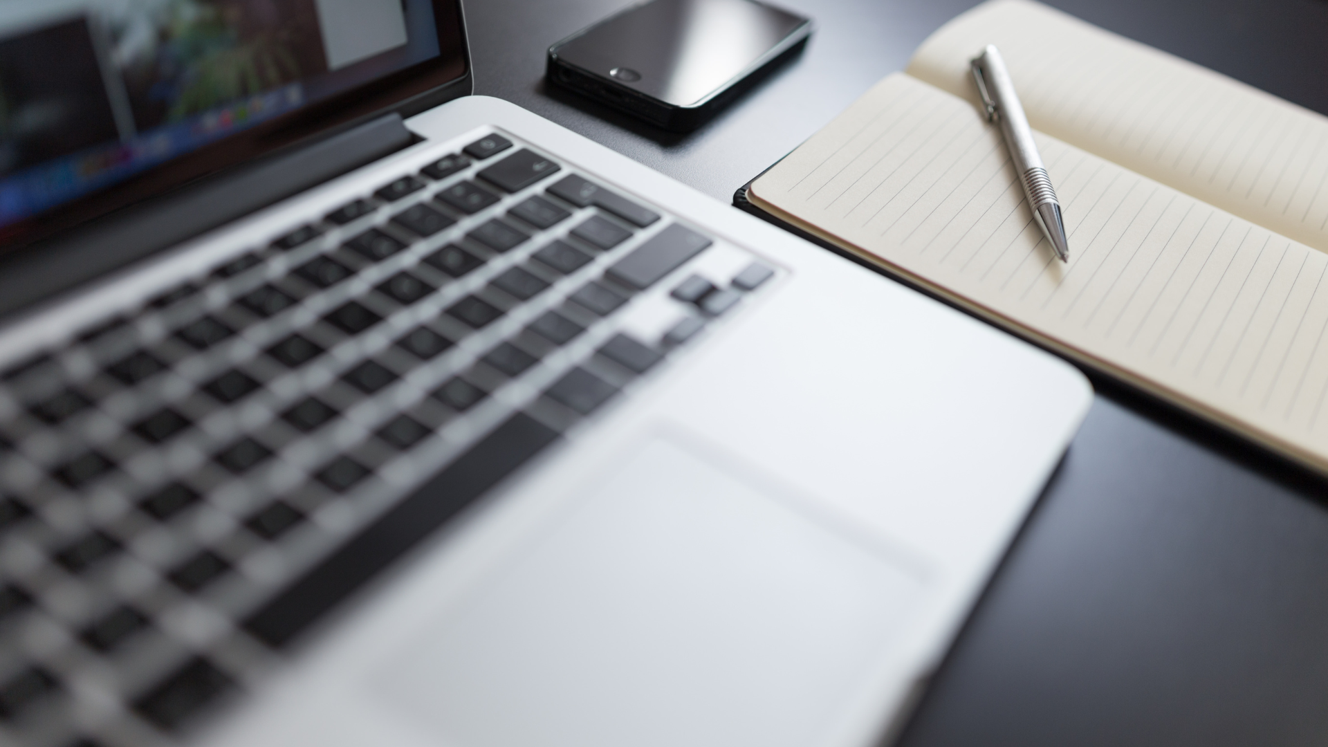 An image of a computer, phone and notepad.